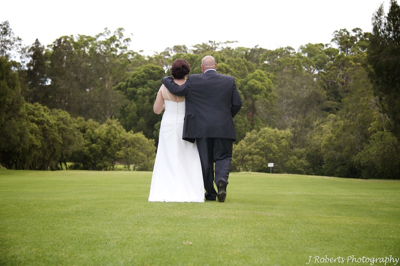 Bride and groom walking away on golf course - wedding photography sydney